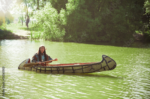 North American Indian floats down the river on a canoe photo