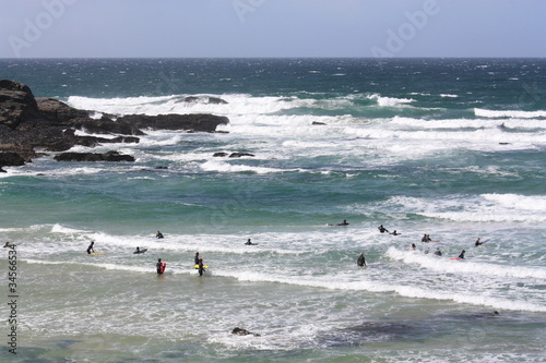 rough stormy sea on cornwall coast with surfers surfing