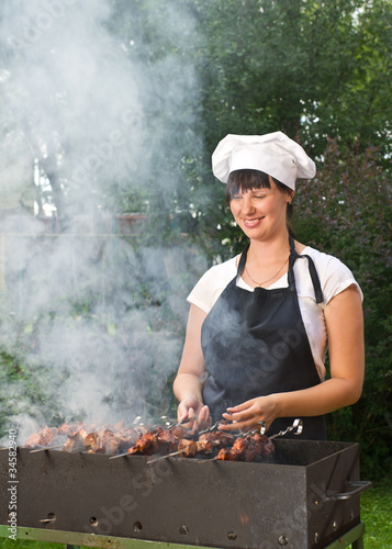 Young woman cook preparing meat in brazier