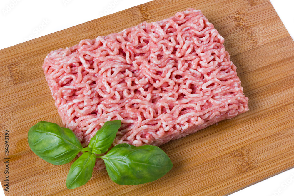 minced meat with basil on a wooded cutting board minced meat with basil on a wooded cutting board