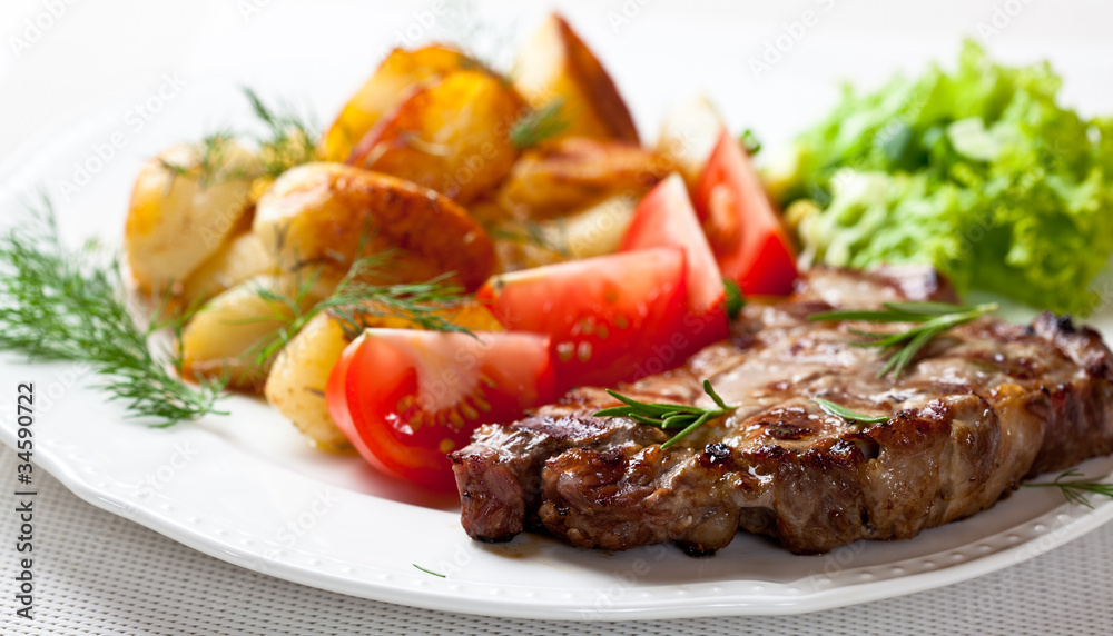 Grilled pork steak with roasted potatoes and herbs