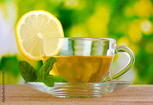 tea with lemon on green leaves background
