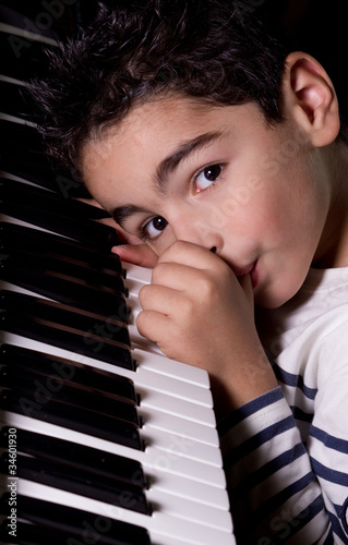 Enfant qui tète son pouce sur le piano photo