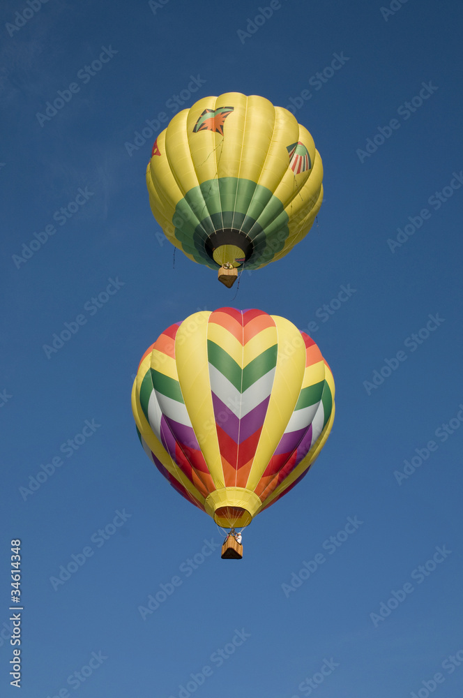 Two hot-air balloons flying vertically aligned