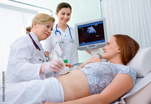 Pregnant woman getting ultrasound diagnostic from doctor