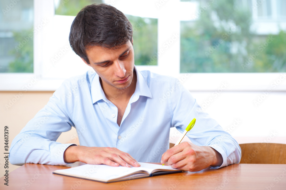 Businessman sitting indoors and writing plan in his diary Businessman sitting indoors and writing plan in his diary