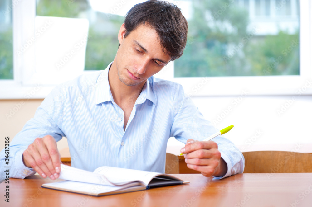 Businessman sitting indoors and writing plan in his diary Businessman sitting indoors and writing plan in his diary