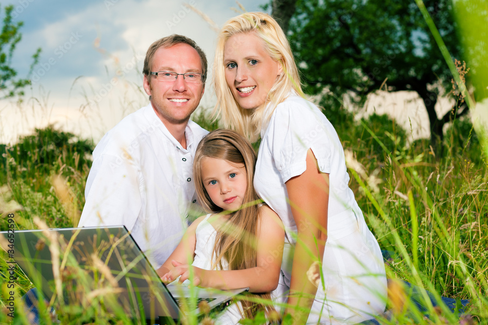 Glückliche Familie sitzt auf Wiese Glückliche Familie sitzt auf Wiese