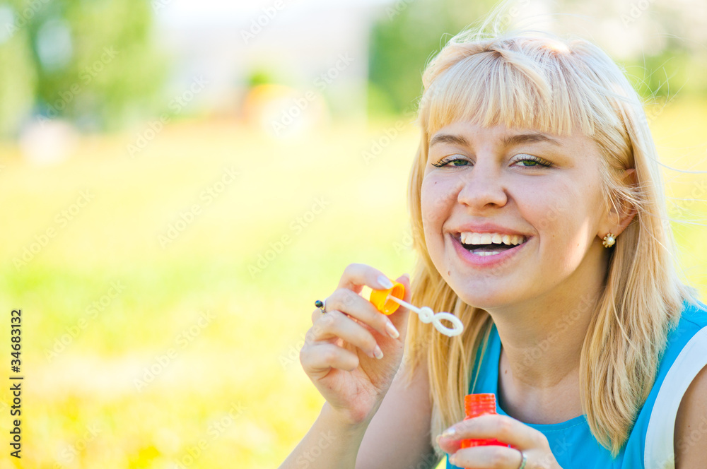 .Woman blowing bubbles in park .Woman blowing bubbles in park