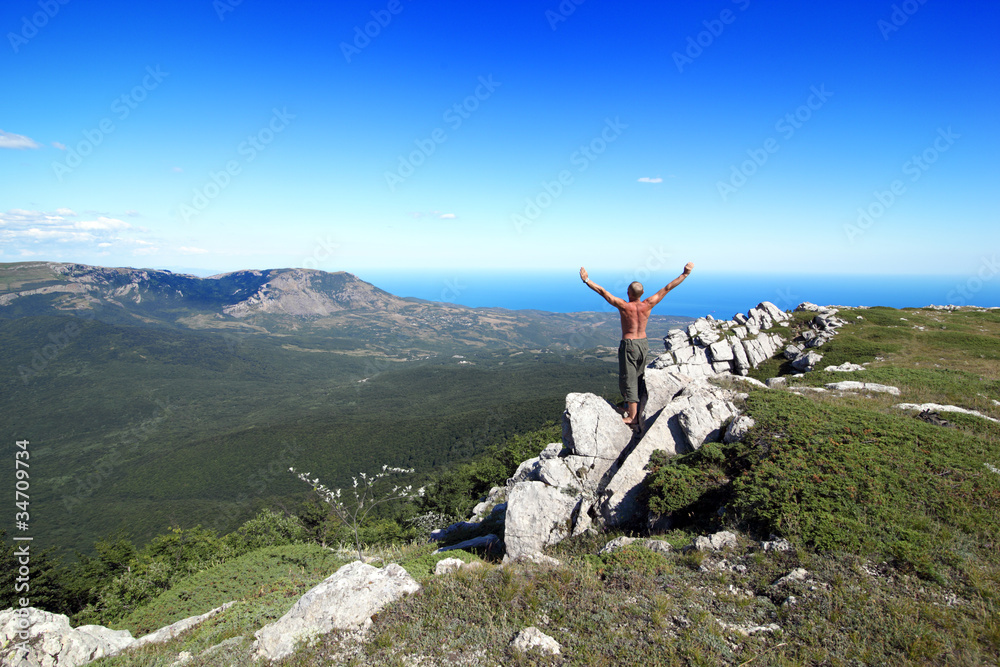 sports man costs on a rock, having lifted upwards hands