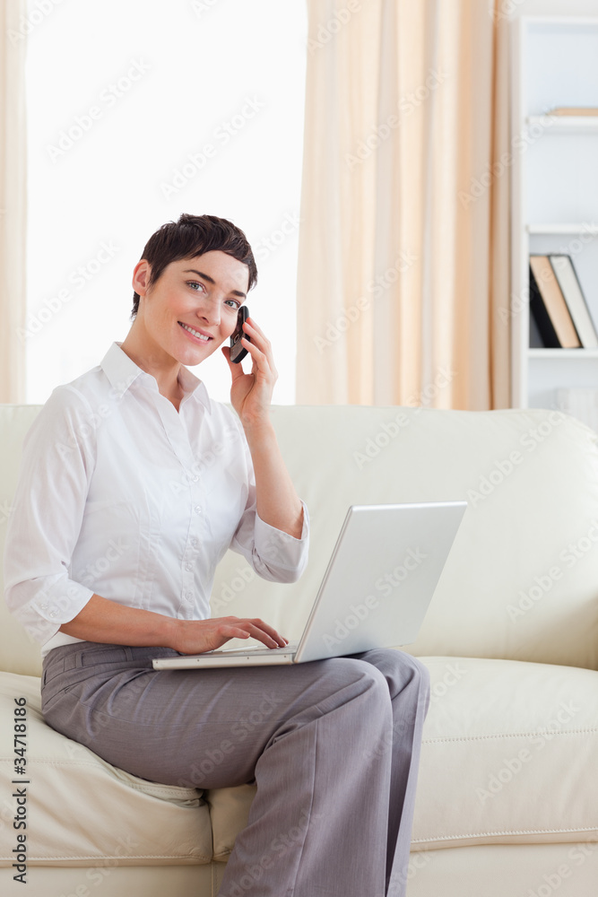 Cute Woman with a laptop and a phone looking into the camera Cute Woman with a laptop and a phone looking into the camera