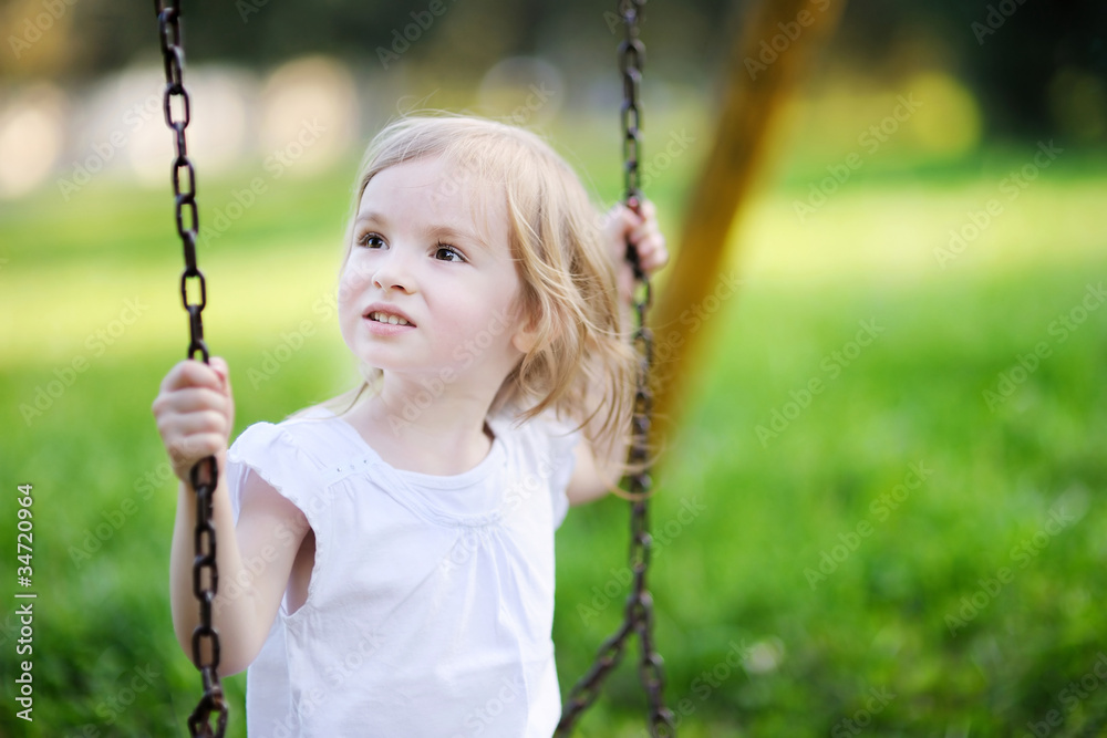 Adorable little girl having fun on a swing