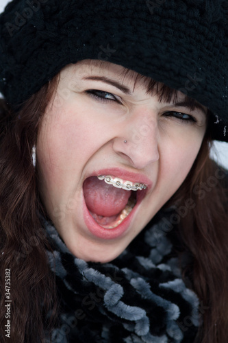Junge schreiende Frau mit Zahnspange Mütze und Schal