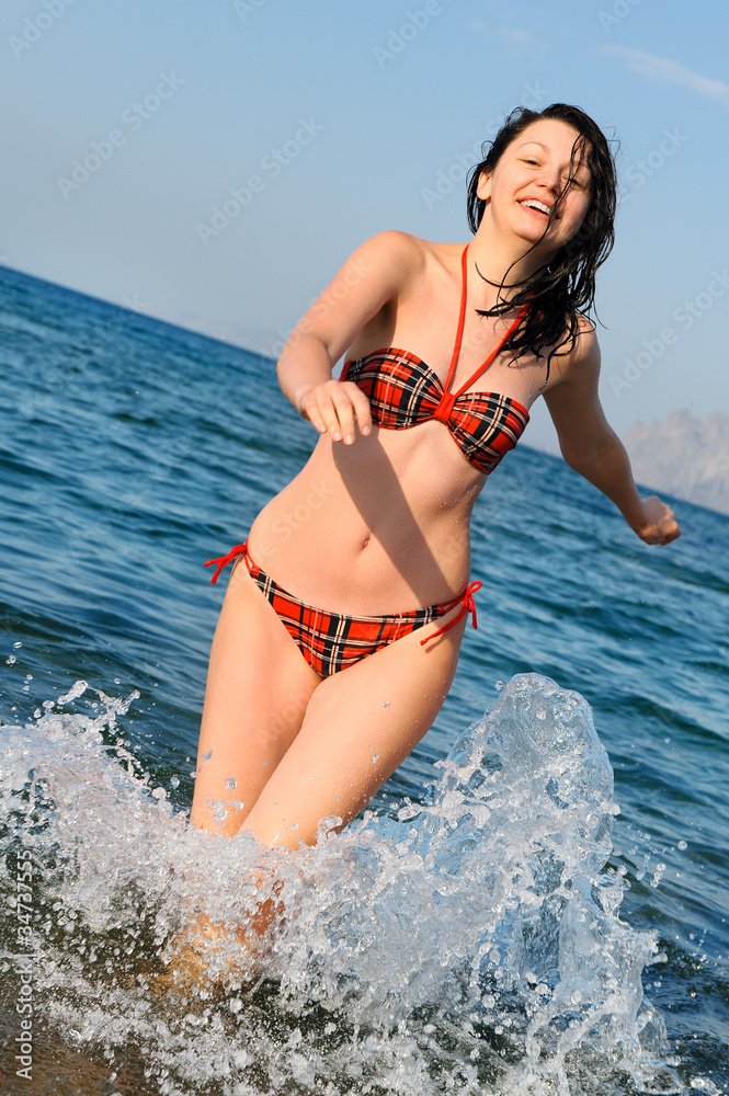 Fototapeta premium The joyful woman runs on sea water