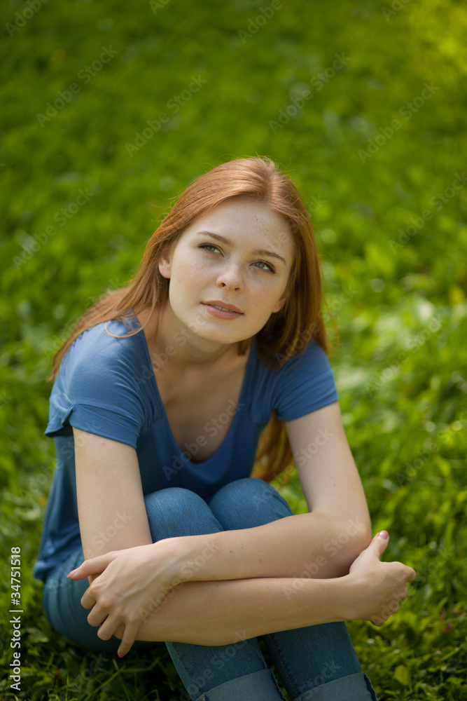 beautiful red-haired girl sitting on grass beautiful red-haired girl sitting on grass