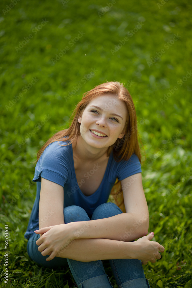 beautiful red-haired girl sitting on grass beautiful red-haired girl sitting on grass