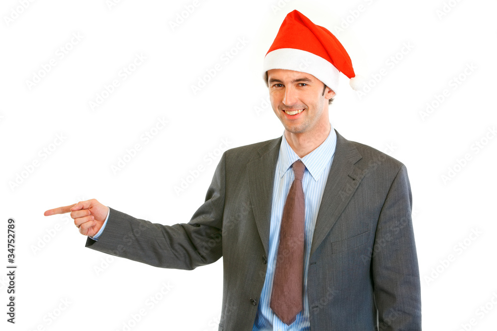 Smiling businessman in Santa hat pointing finger at copy space Smiling businessman in Santa hat pointing finger at copy space