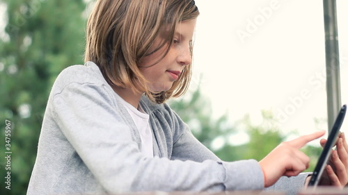 Young teenage girl with tablet computer outdoors, dolly   shot