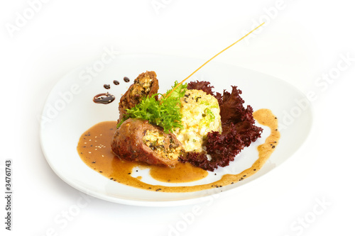 Meat roll with mashed potatoes, salad and sauce on white plate