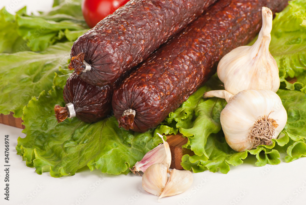 Salami with lettuce, garlic and tomatoes on white background