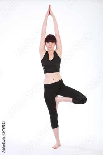 Beautiful fit woman in Yoga Tree Pose Vrksasana