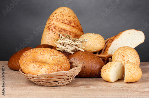rye and white bread and buns on wooden table on gray background