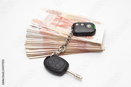 Car keys on stack of money on white background