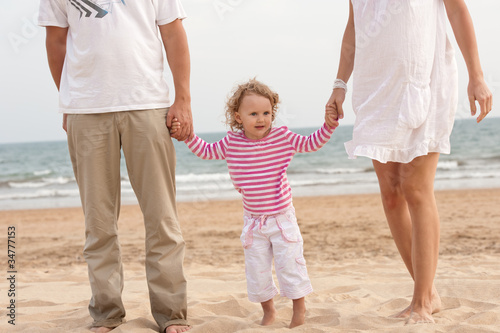 Family parents and baby walking on the beach