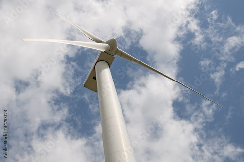 Wind turbine against a sky blue background with clouds
