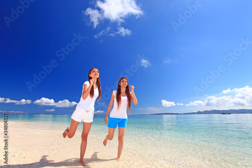 波打ち際を走る二人の笑顔の女性