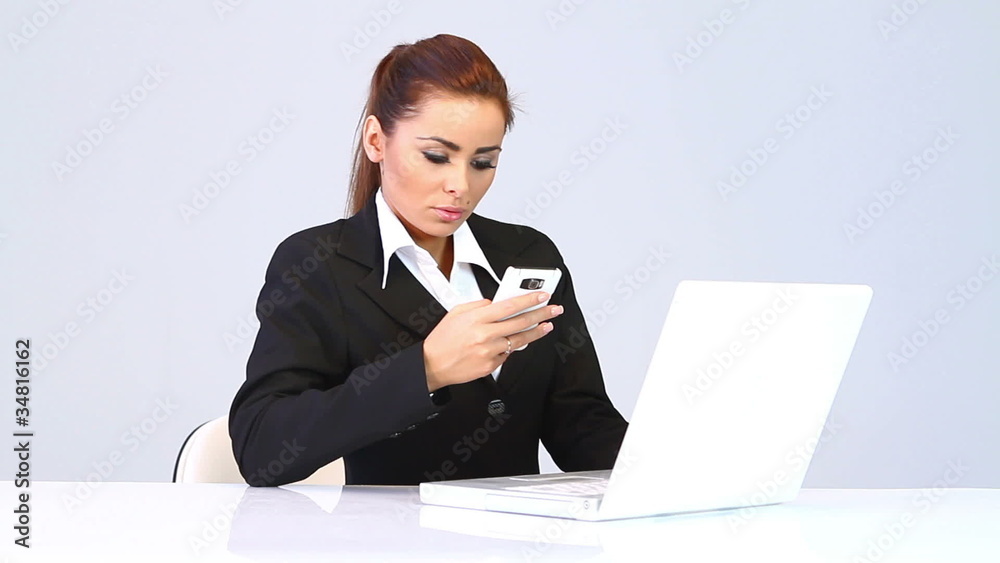 Business woman sitting at the desk and talking mobile phone Business woman sitting at the desk and talking mobile phone