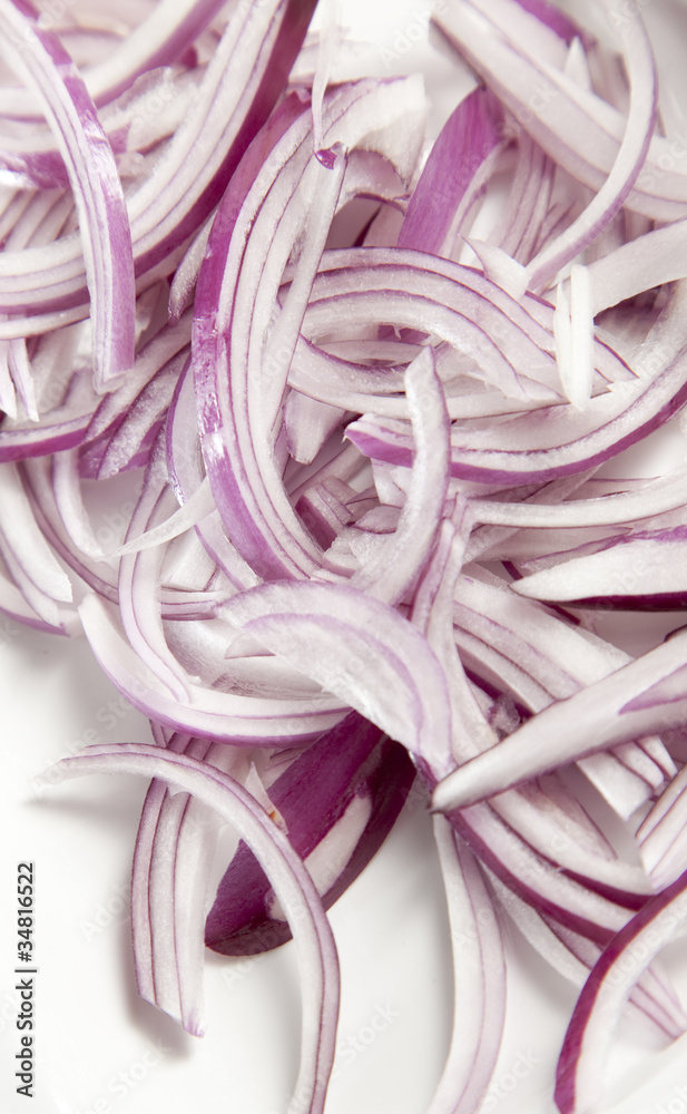 Sliced Red Onion rings on whte chopping board.