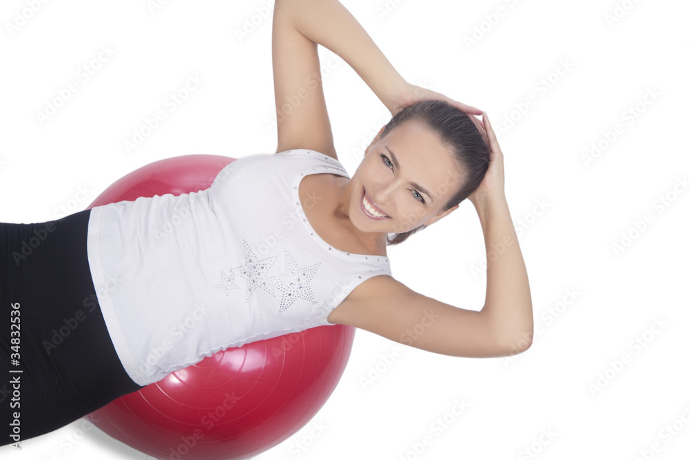 Fototapeta premium happy and smiling brunette girl with red fitball isolated on whi