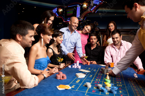 Fotografia happy friends playing roulette in a casino