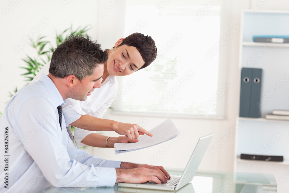 Office workers comparing a blueprint folder to an electronic one Office workers comparing a blueprint folder to an electronic one