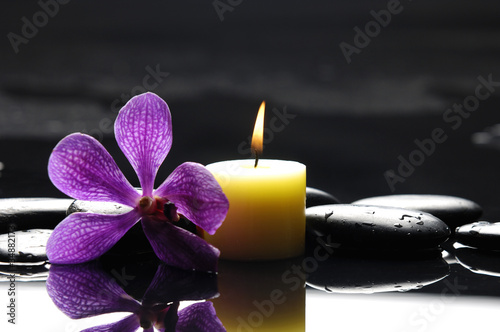 burning spa candles with pink orchid and stones reflection