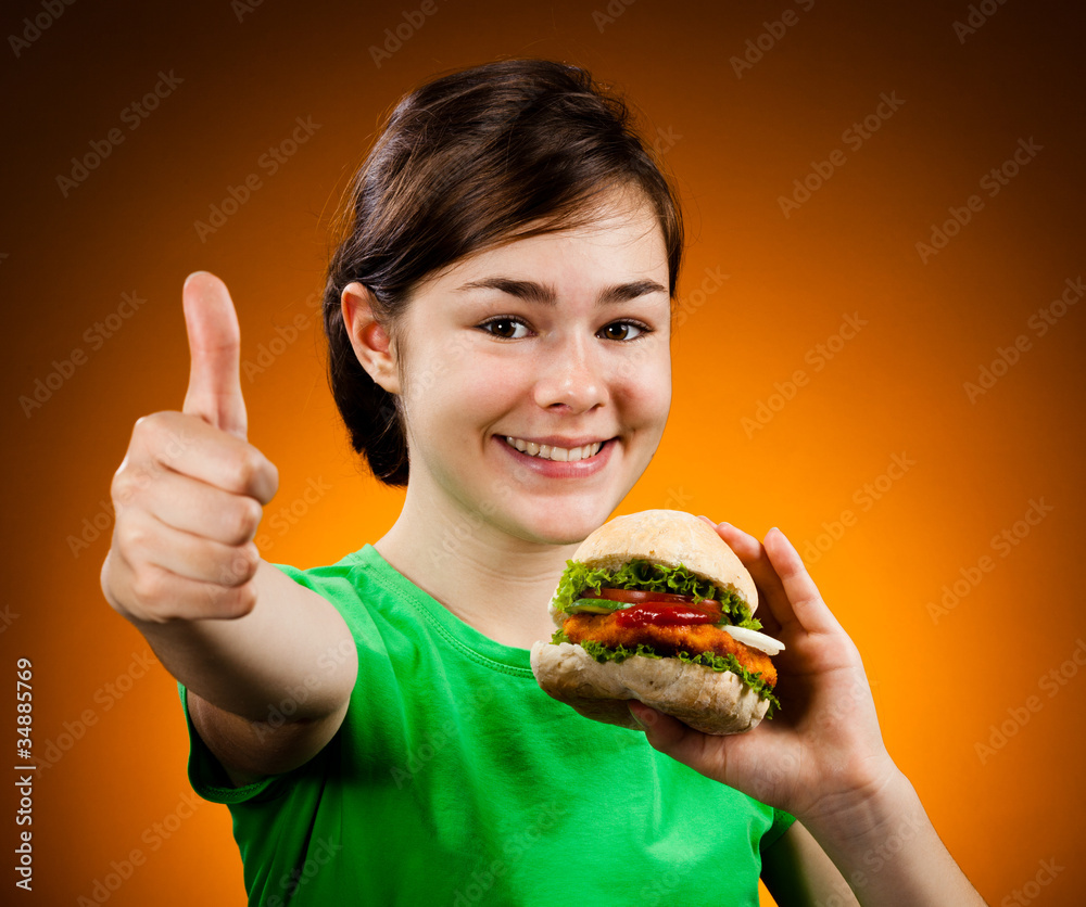 Girl eating big hamburger showing OK sign Girl eating big hamburger showing OK sign