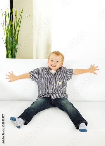 Fototapeta Naklejka Na Ścianę i Meble -  little son sitting on sofa in the room