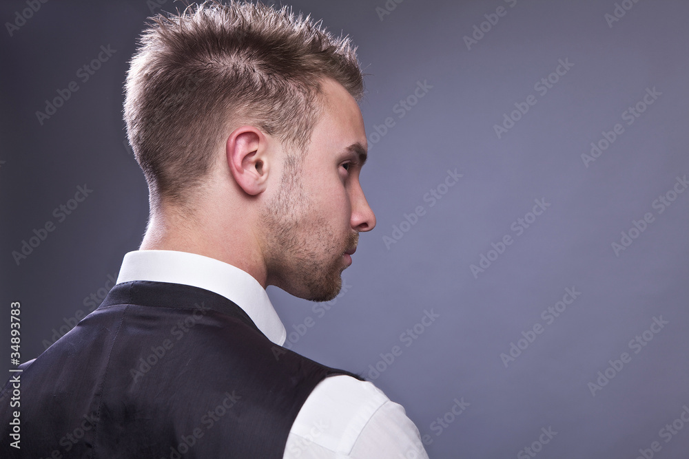 Young business man from back, isolated on gray.