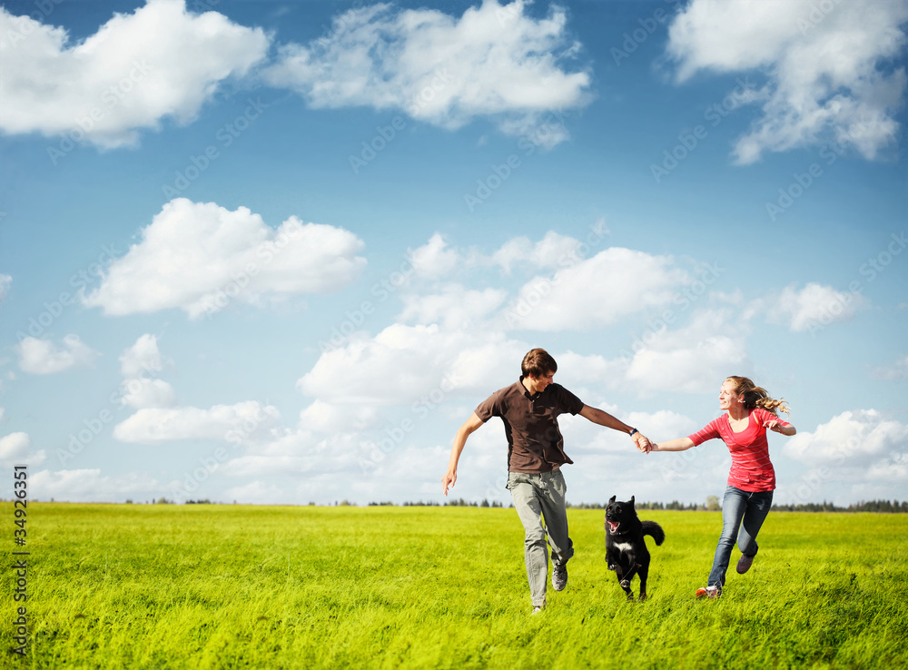 Young happy family running with dog on a green meadow Young happy family running with dog on a green meadow