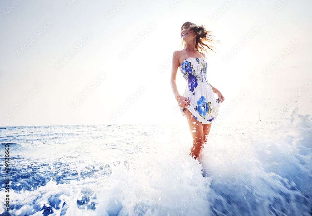 Young smiling woman having fun standing in blue sea water