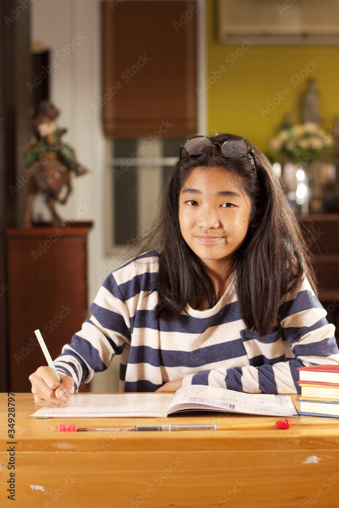 a girl acting clever and smile on her homework book.