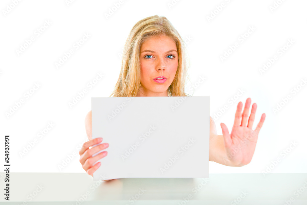 Concerned girl holding blank paper and showing stop gesture Concerned girl holding blank paper and showing stop gesture
