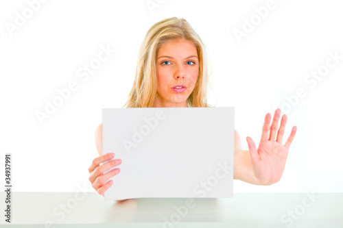 Concerned girl holding blank paper and showing stop gesture