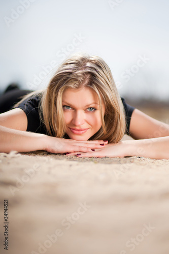 Beautiful blonde girl lying on sand at the beach in rainy day photo