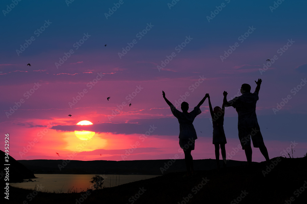 The family from three persons welcomes the sunset sun