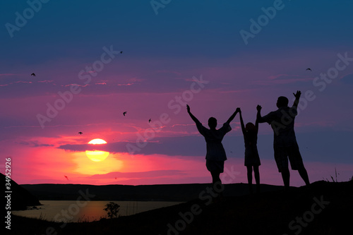 The family from three persons welcomes the sunset sun