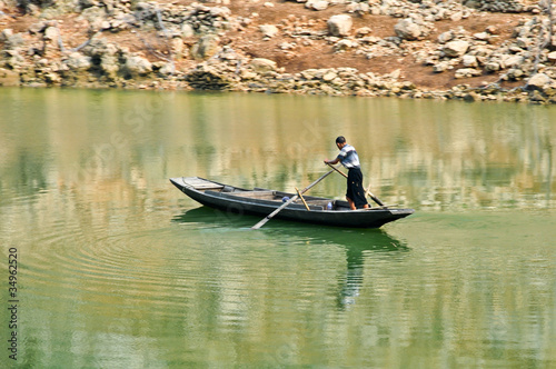 lone chinese fisherman rowing on a river