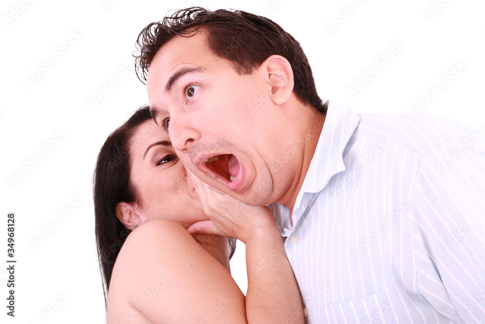 Fototapeta premium Woman tells something into surprised guy's ear isolated on white