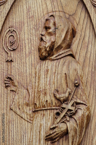 scultura di frate santo su portone di chiesa in legno